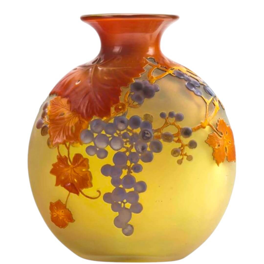 Artistic glass vase with vibrant grape and leaf patterns in warm amber and yellow tones.